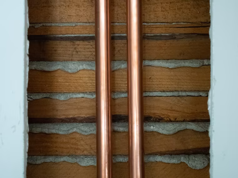 Due tubi in rame a vista nella sezione di una parete, durante un intervento idraulico